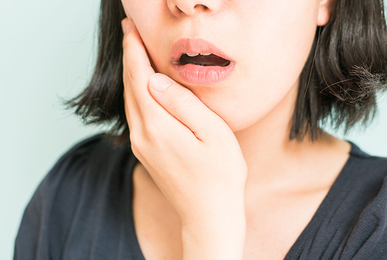 歯の痛みを感じ顎を抑える女性